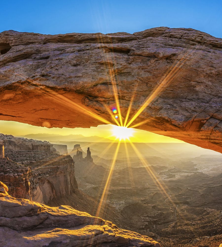 A partial view of the underside of a sandstone arch overlooking the vast hills and valleys of Arches National Park in Moab, Utah.