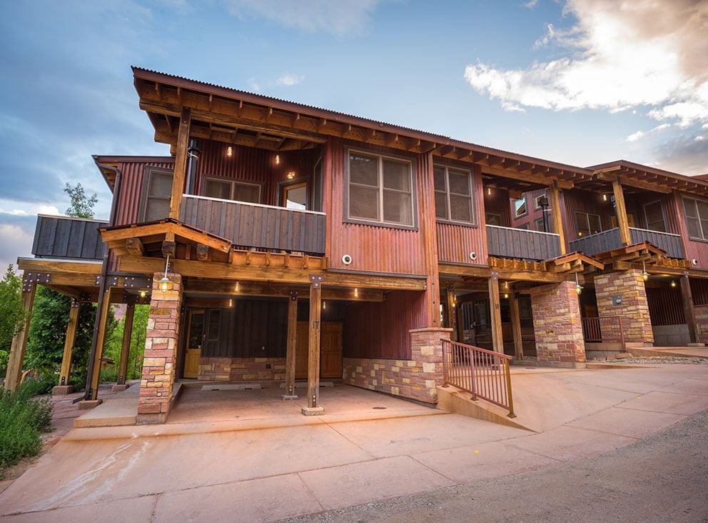 A photo of two storey townhouse units at Moab Springs Ranch with a large square window, covered balcony on the upper level and a two-car garage immediately beneath it