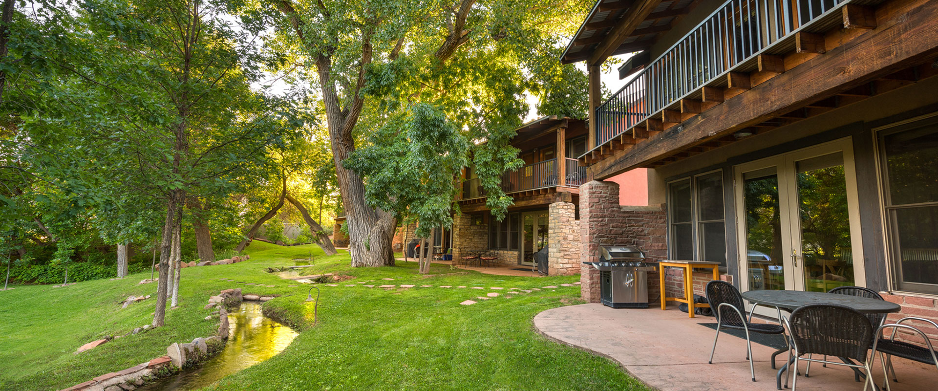 A large aerial view over the sandstone cliffs, the cottonwood tree tops and the sloping white and brown roofs of bungalows and townhomes at Moab Springs Ranch.