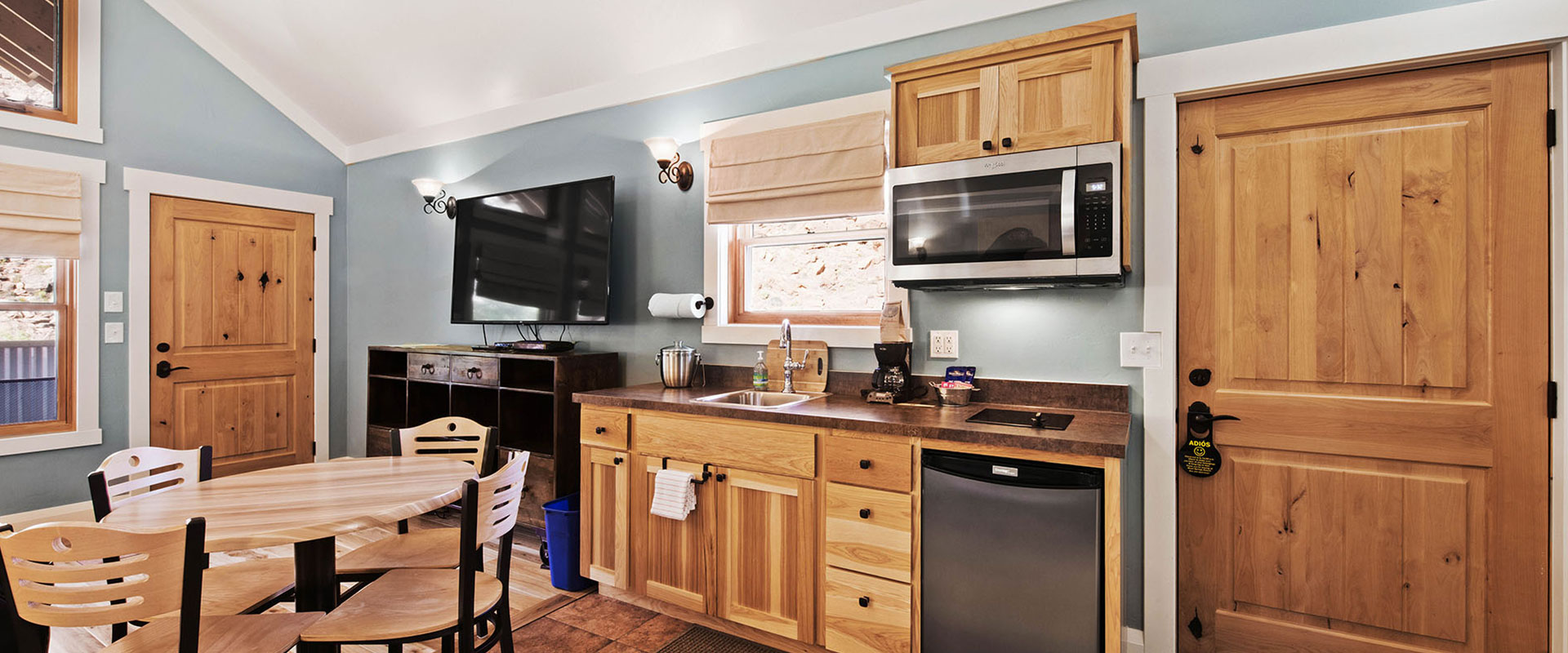 The fully equipped kitchen at Unit #18 at Moab Springs Ranch features honey wood color cupboards, gas stove, brown tile backsplash and countertops, and a wrap around island.