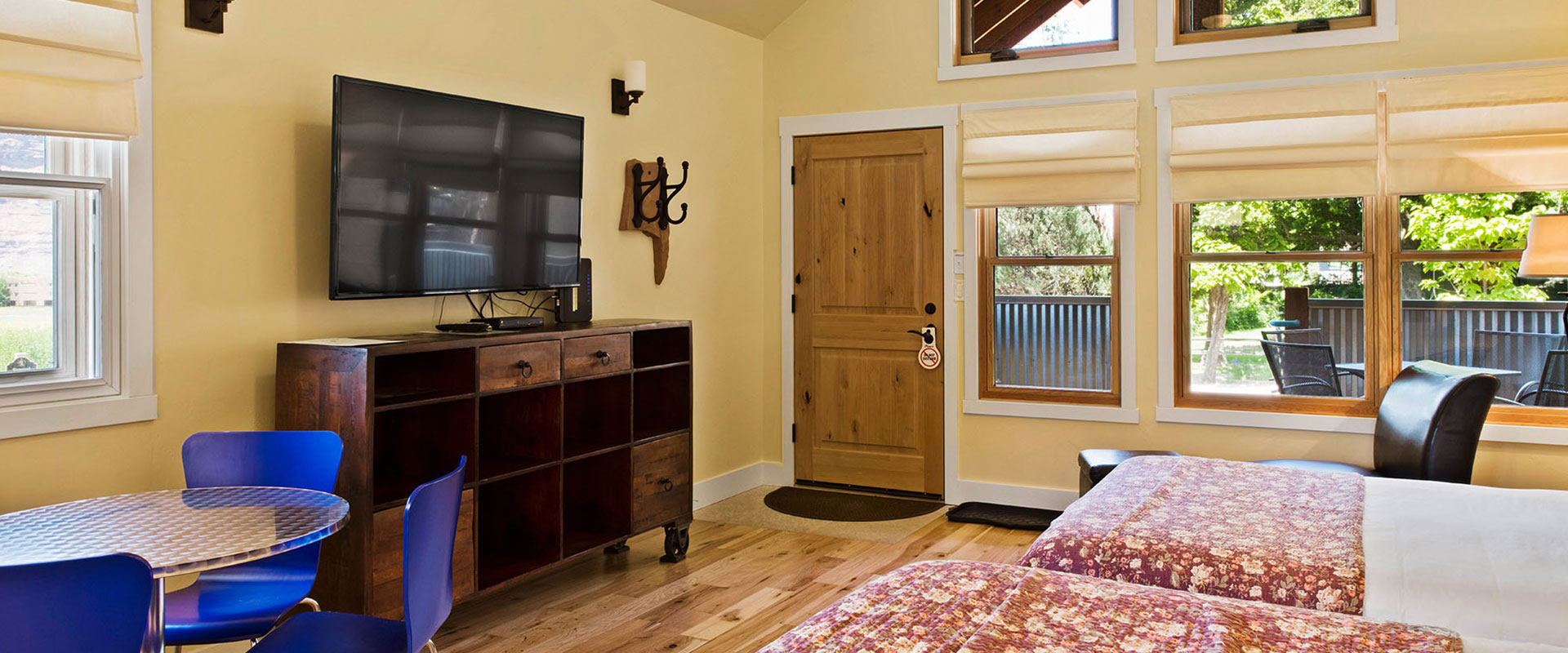 A black wood framed queen sized bed, covered in a multi-colored geographical print is presented with three large white pillows at a bedroom suite in Unit #21 at Moab Springs Ranch.