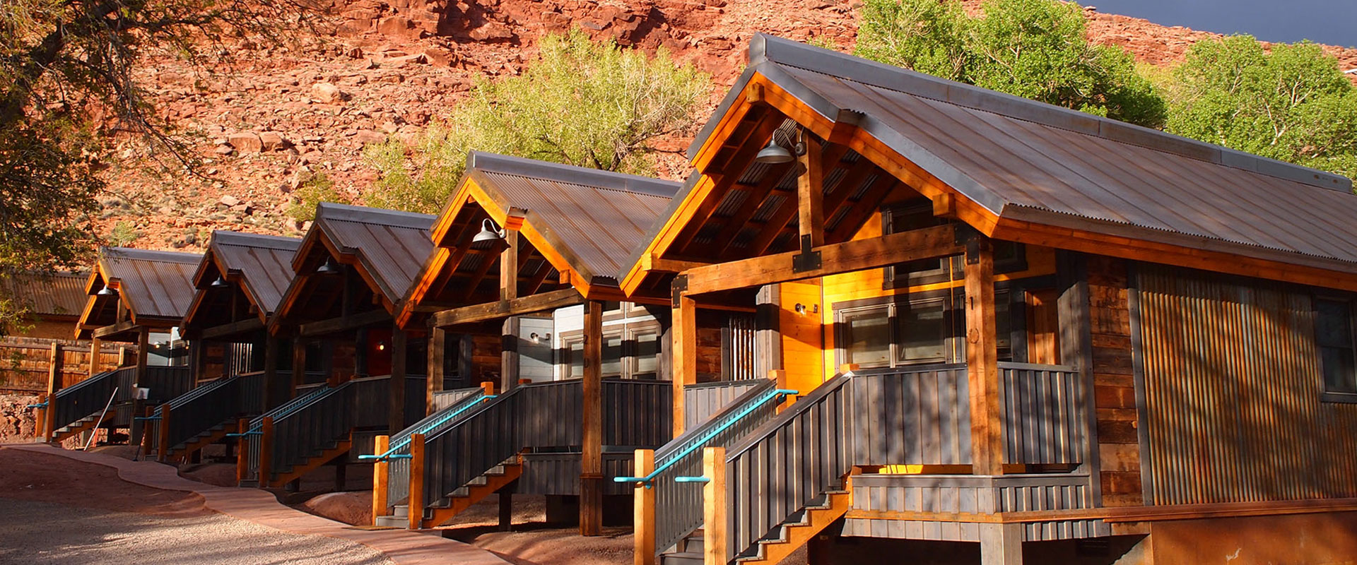 Upward looking view of trees bearing green and yellow leaves towering over the townhomes of Moab Springs Ranch.