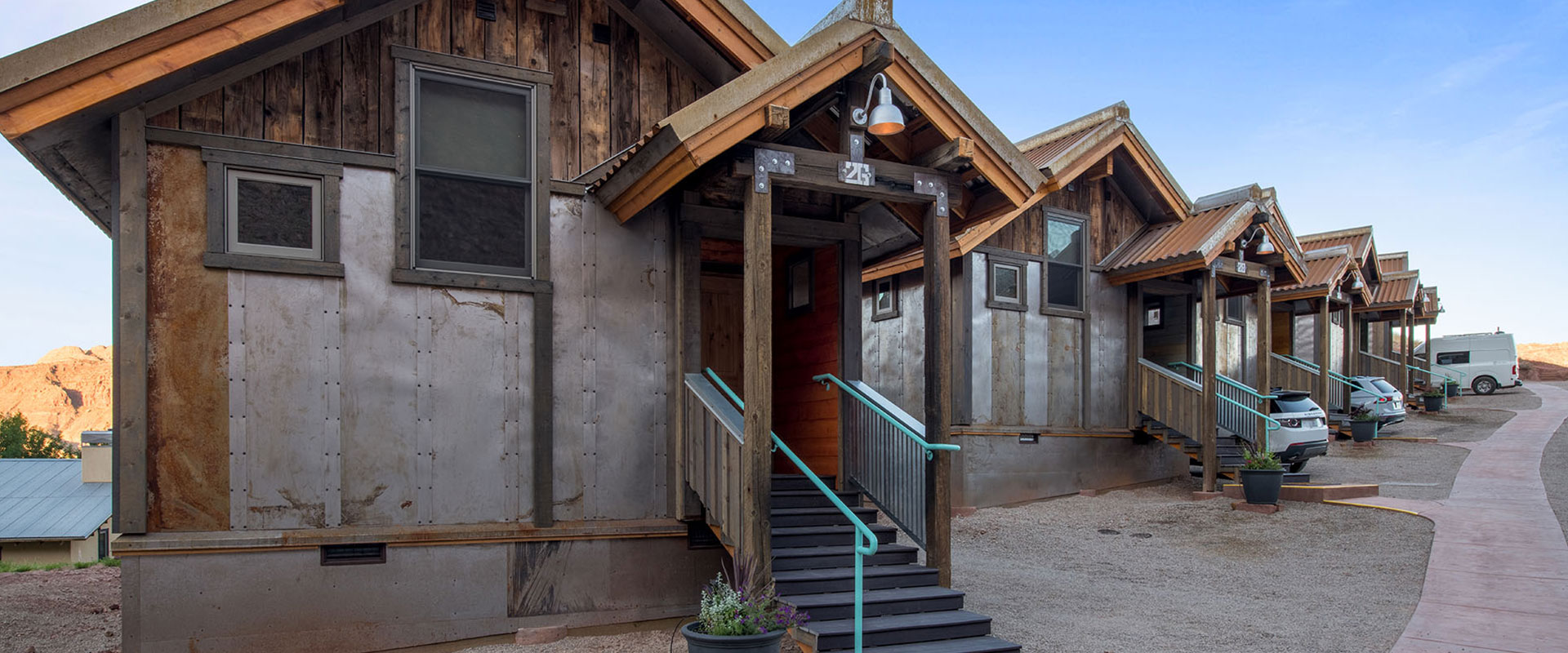 A view of the two-car garage spaces of Units #17 and 18 at Moab Springs Ranch, with brick and wood columns, ceiling lighting and cement car stops.