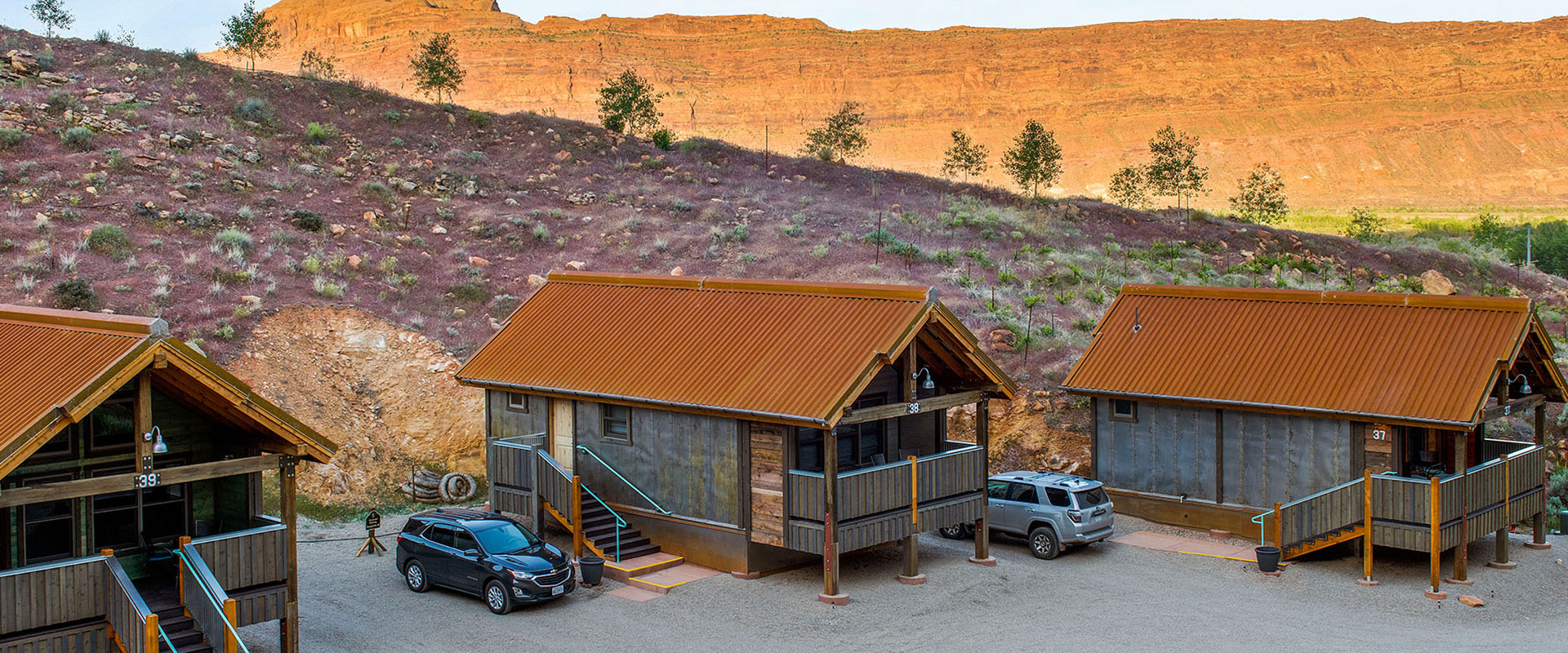 A shallow stream, trees and an outdoor picnic table are found in the yard space of townhouse units at Moab Spring Ranch.