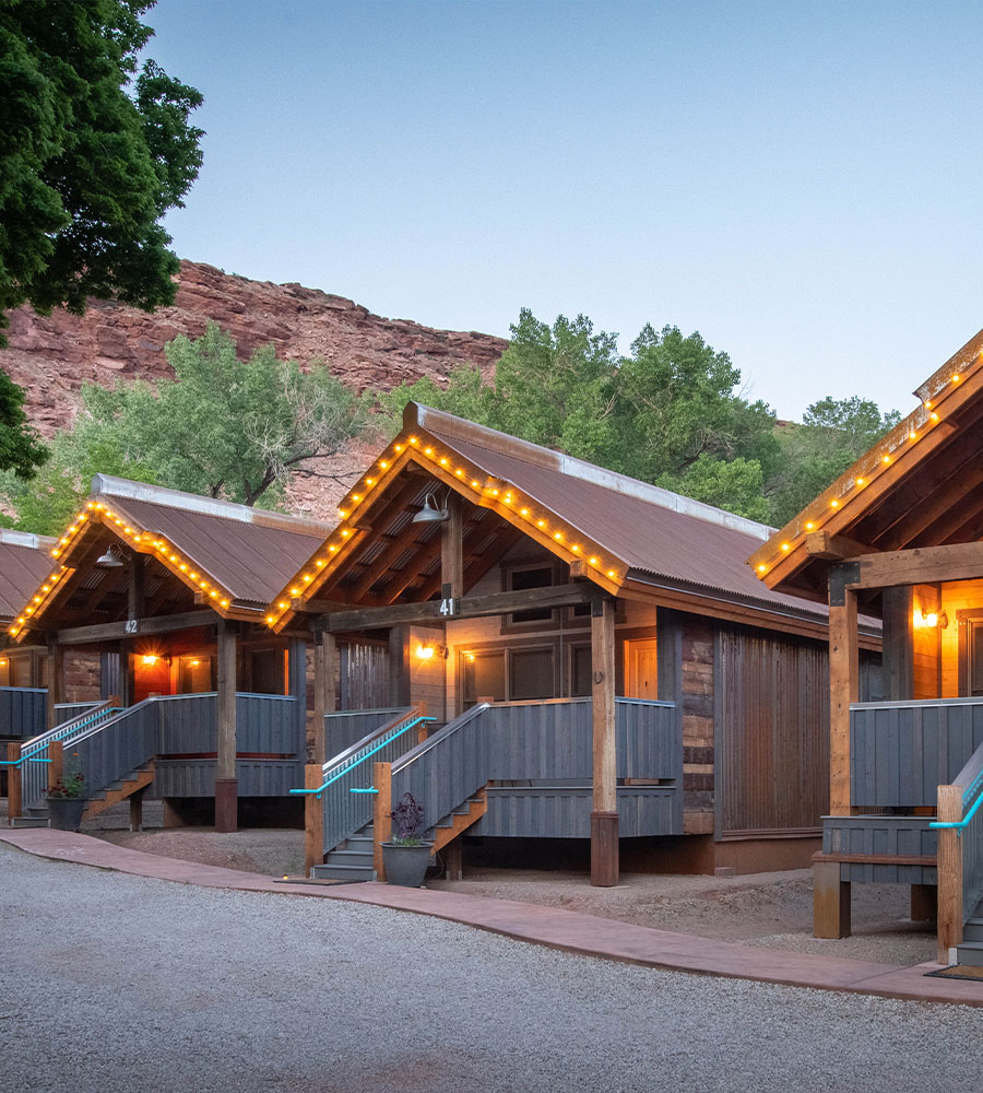 A 3D representation of a natural brown wood bungalow available for guests at Moab Springs Ranch, featuring multiple square windows facing out onto a covered porch.