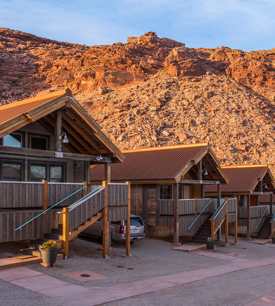 A 3D representation of a natural brown wood bungalow available for guests at Moab Springs Ranch, featuring multiple square windows facing out onto a covered porch.