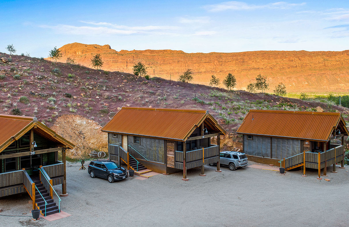 A shallow stream, trees and an outdoor picnic table are found in the yard space of townhouse units at Moab Spring Ranch.