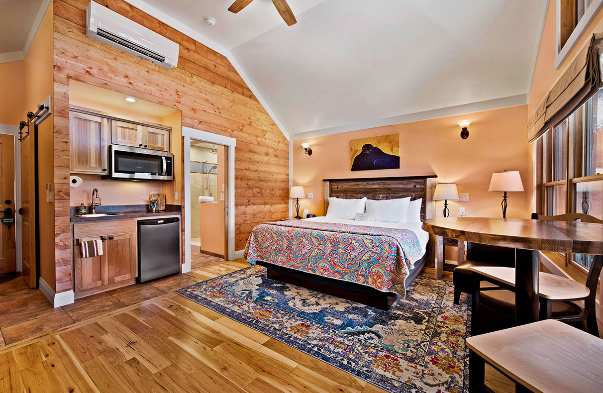 A large view of the kitchen of Unit #18 at Moab Springs Ranch with spacious beige wood cabinets and stainless steel appliances such as stove, refrigerator and microwave.